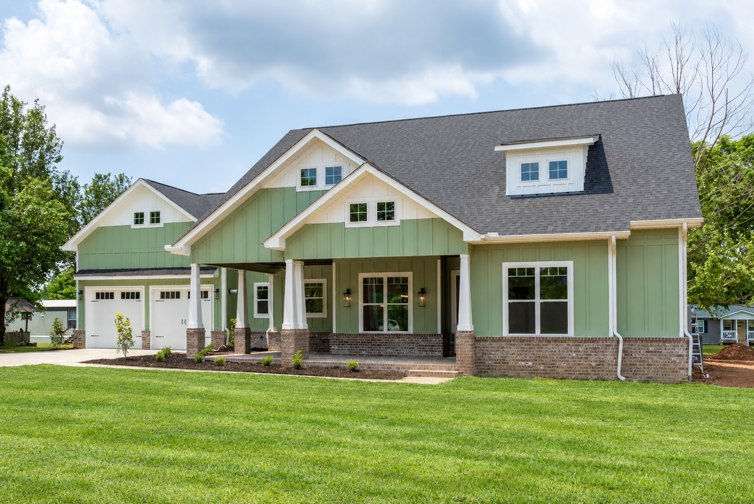 Completed home with green siding, white trim and a welcoming front porch